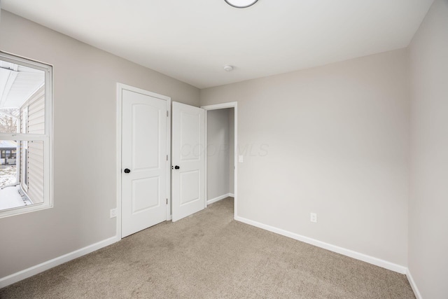 unfurnished bedroom with carpet flooring and baseboards