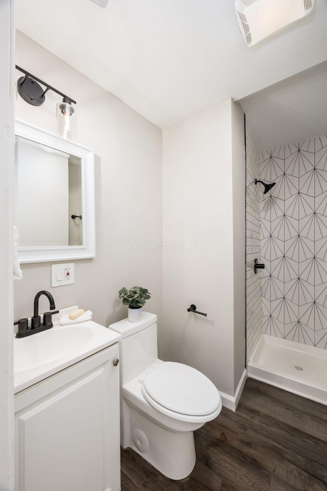 bathroom featuring toilet, a stall shower, wood finished floors, and vanity