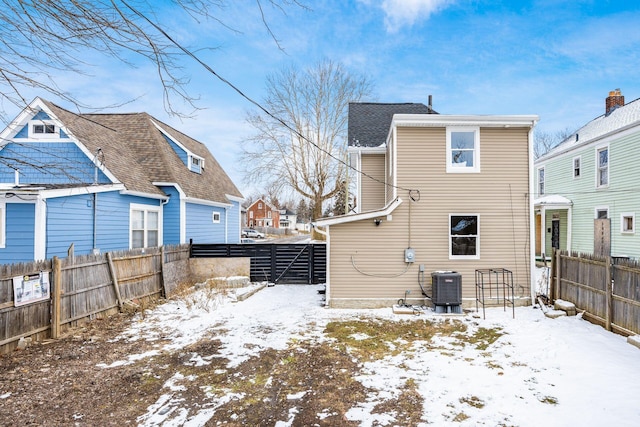 snow covered rear of property with a fenced backyard and central air condition unit