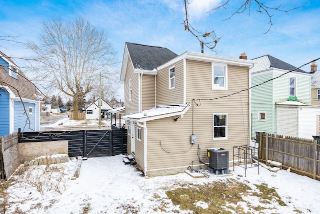 snow covered property featuring a fenced backyard and central air condition unit