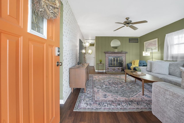 living area featuring a fireplace, visible vents, wood finished floors, and ceiling fan with notable chandelier