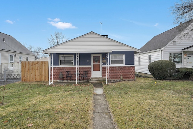 bungalow-style house featuring a front yard, brick siding, and fence