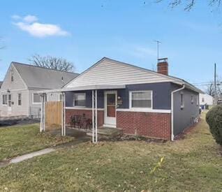 bungalow with a front lawn, a chimney, and brick siding