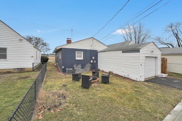 back of property featuring aphalt driveway, an outbuilding, a yard, central AC unit, and fence