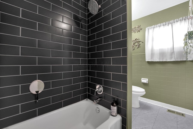 full bathroom featuring visible vents, toilet, tile patterned floors, bathtub / shower combination, and tile walls