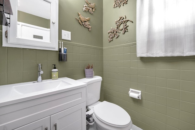 bathroom with tile walls, vanity, and toilet