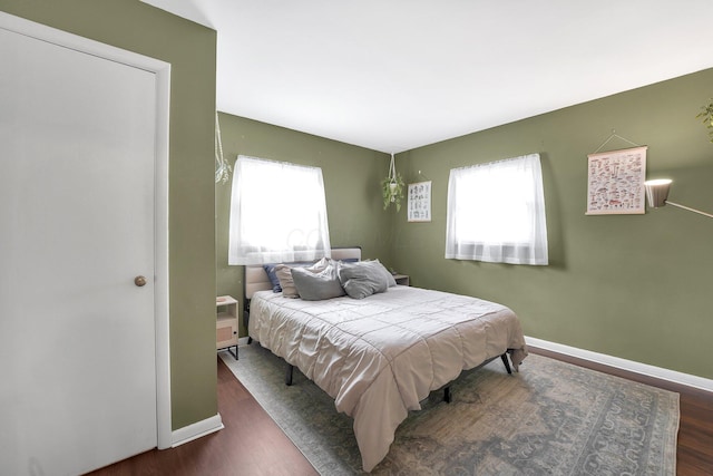 bedroom featuring multiple windows, baseboards, and wood finished floors