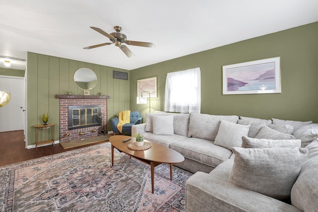 living area with ceiling fan, a fireplace, wood finished floors, and visible vents