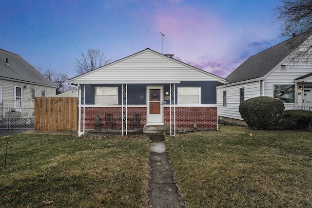 bungalow-style home featuring brick siding, a front yard, and fence