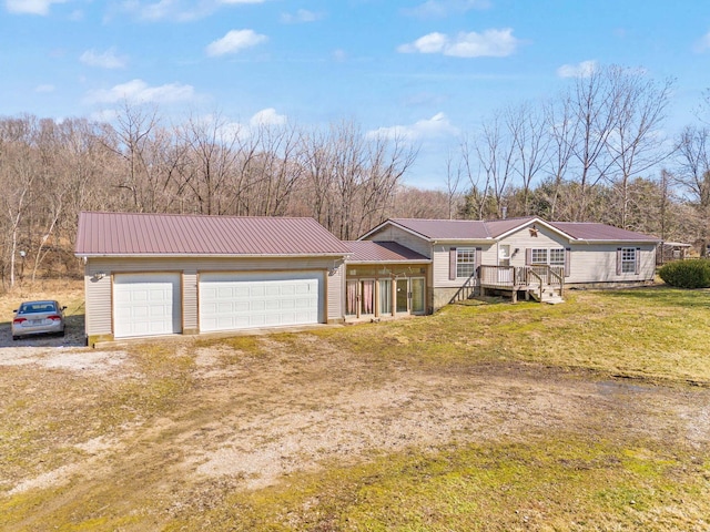 view of front of home with dirt driveway, metal roof, and a front yard