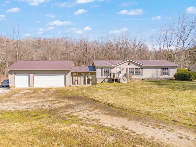 view of front of property featuring a garage, a front yard, metal roof, and dirt driveway