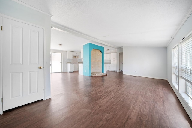 unfurnished living room with a textured ceiling, vaulted ceiling, dark wood finished floors, and baseboards