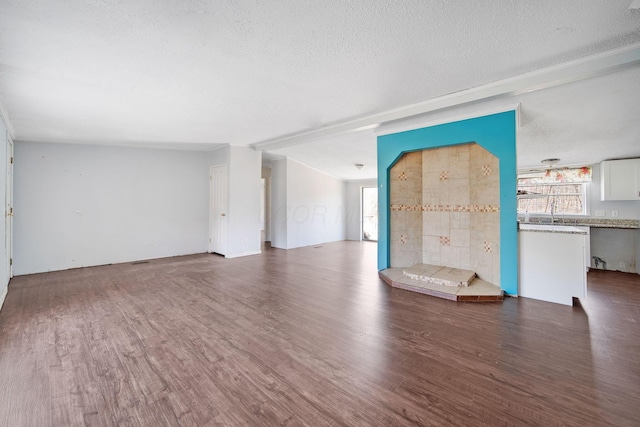 unfurnished living room featuring a textured ceiling and wood finished floors