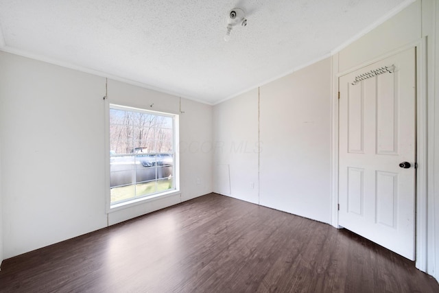 spare room featuring crown molding, dark wood finished floors, and a textured ceiling