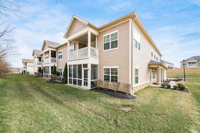 back of house featuring a balcony, a sunroom, and a yard