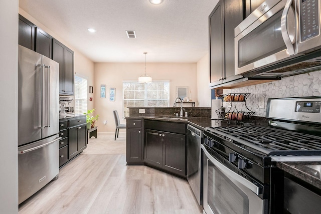 kitchen with tasteful backsplash, dark stone counters, a peninsula, stainless steel appliances, and a sink