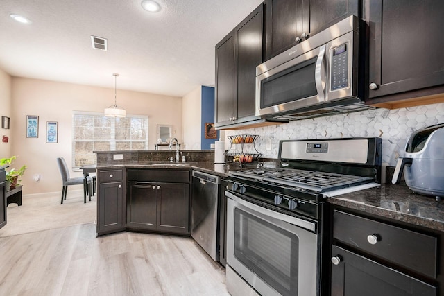 kitchen with visible vents, appliances with stainless steel finishes, a peninsula, a sink, and backsplash