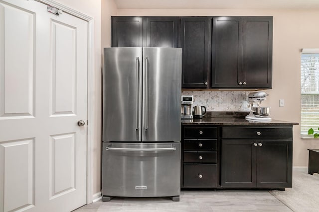 kitchen featuring dark cabinets, dark stone countertops, freestanding refrigerator, and baseboards