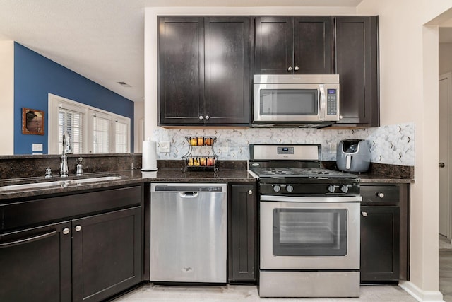 kitchen featuring a sink, visible vents, appliances with stainless steel finishes, backsplash, and dark stone countertops