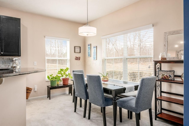 dining room featuring light colored carpet and baseboards