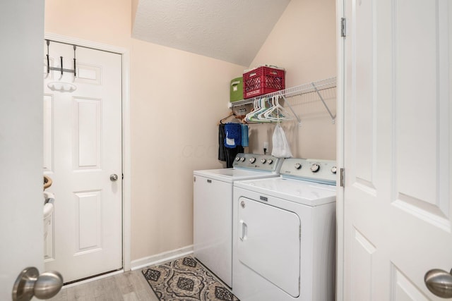 laundry room with washing machine and clothes dryer, a textured ceiling, light wood-type flooring, laundry area, and baseboards