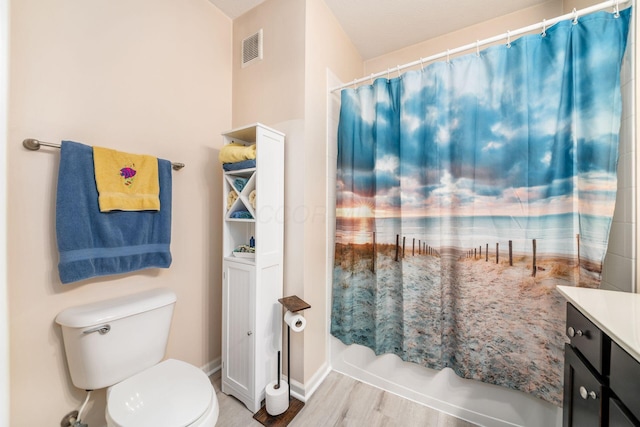 bathroom featuring toilet, wood finished floors, vanity, visible vents, and shower / tub combo with curtain