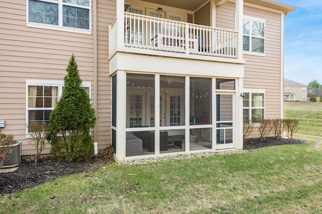 back of house with a balcony, a sunroom, and a yard