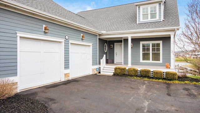 view of front of house with driveway, an attached garage, a porch, and roof with shingles