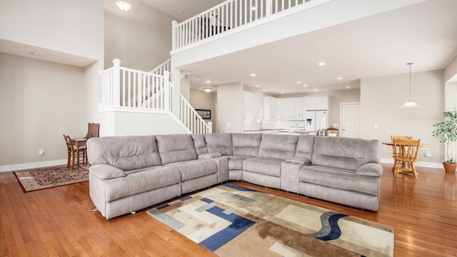 living room featuring stairway, light wood-style flooring, and baseboards