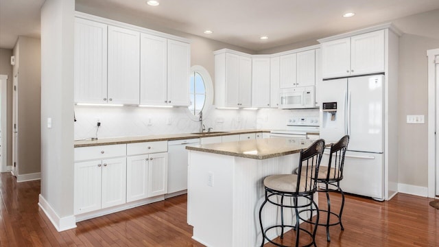 kitchen with white appliances, white cabinetry, and a center island