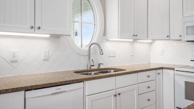 kitchen with white appliances, tasteful backsplash, white cabinets, and a sink