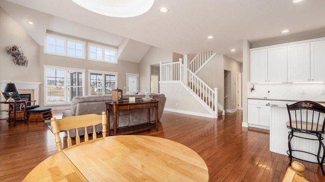 dining room featuring recessed lighting, stairway, dark wood finished floors, and a glass covered fireplace