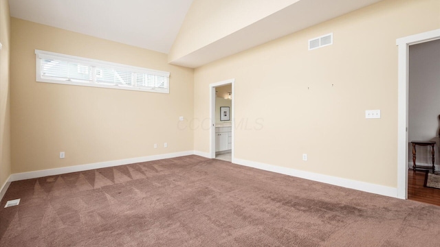 unfurnished room featuring baseboards, visible vents, vaulted ceiling, and carpet flooring