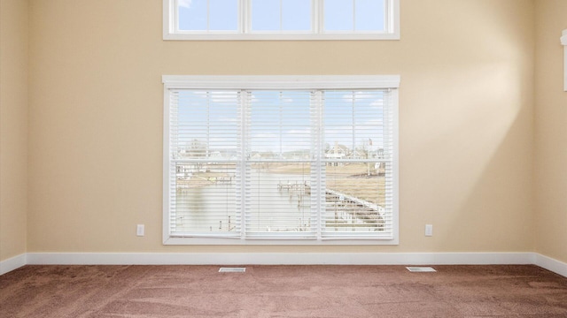 carpeted spare room with visible vents and baseboards