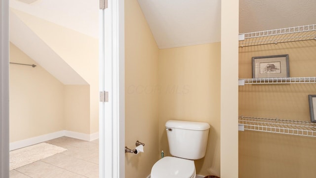 bathroom with lofted ceiling, baseboards, toilet, and tile patterned floors