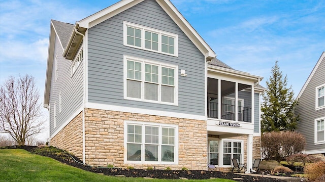 back of property with a sunroom and stone siding