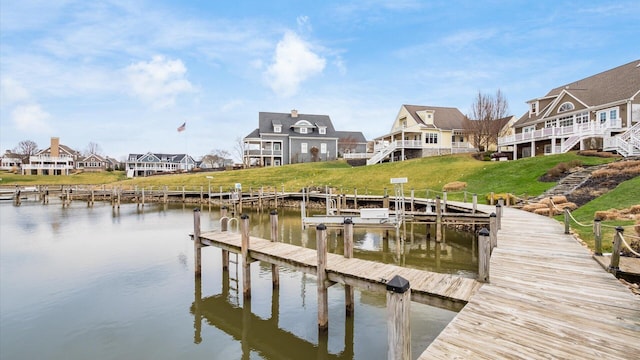 view of dock with a lawn, a water view, and a residential view