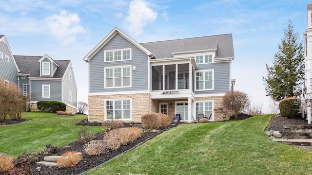 back of house featuring stone siding, a sunroom, and a yard