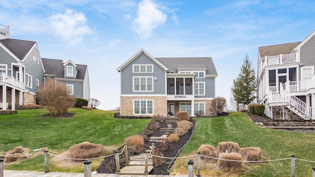 view of front of home featuring a front yard, a sunroom, fence, and stairway