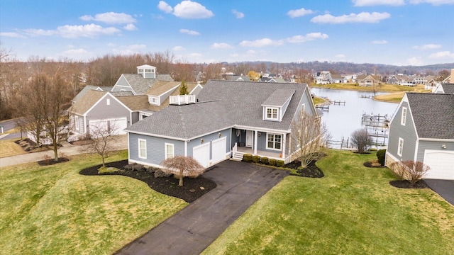 view of front of home with a residential view, aphalt driveway, a water view, an attached garage, and a front lawn