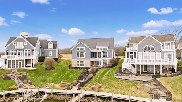 back of house with a patio, a yard, a deck with water view, a balcony, and stairs