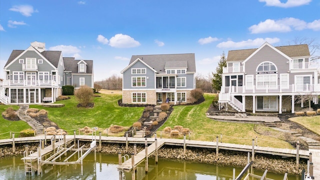 rear view of property featuring a water view, a yard, stairway, and a balcony