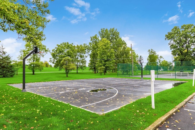 view of basketball court with a tennis court, community basketball court, fence, and a yard