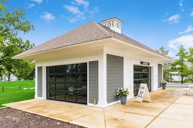 exterior space featuring a shingled roof, a patio area, and a lawn