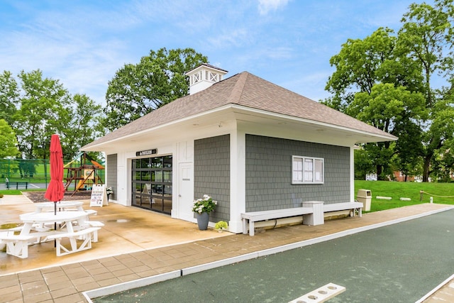 view of side of property featuring a garage, a shingled roof, a lawn, fence, and an outdoor structure