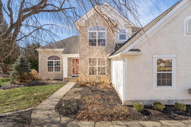 view of front of property with stucco siding, stone siding, and roof with shingles