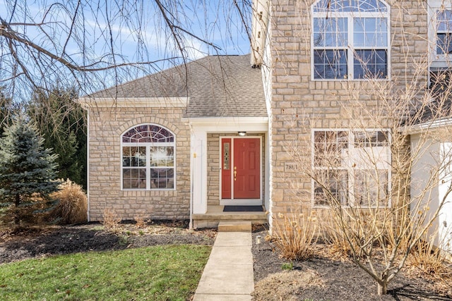 view of front of house featuring stone siding and roof with shingles