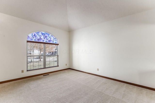 carpeted empty room featuring lofted ceiling, visible vents, a textured ceiling, and baseboards