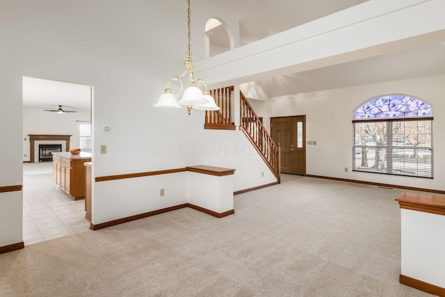 spare room featuring stairs, a fireplace, a wealth of natural light, and light colored carpet