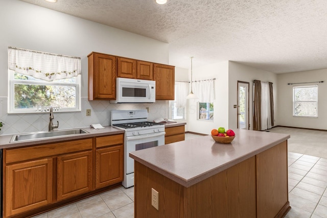 kitchen featuring brown cabinetry, white appliances, a sink, and tasteful backsplash